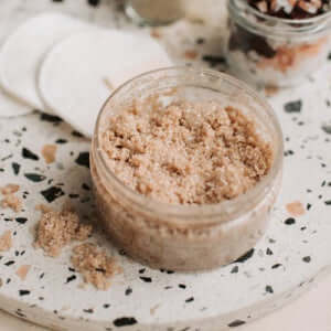 Exfoliating Body Scrubs in a jar on a speckled surface, ideal for achieving healthy glowing skin.