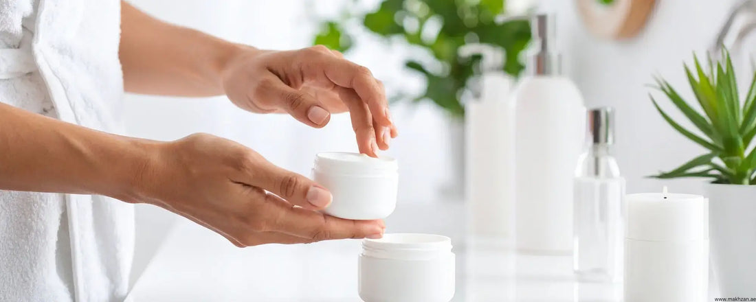 A person applying face cream from a jar in a bright bathroom with plants, highlighting skincare routines.