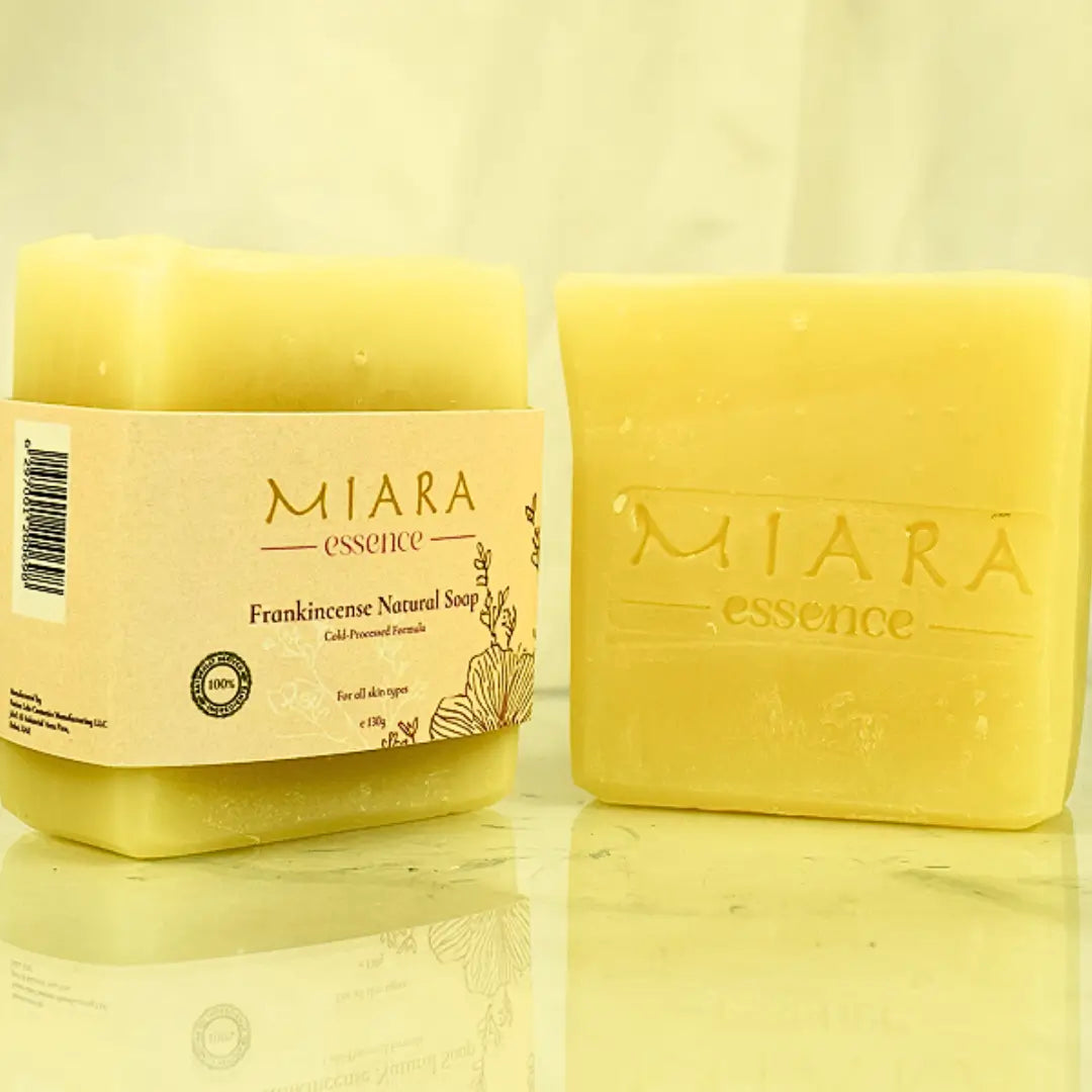 Yellow soap bar and jar with 'MIARA essence frankincense natural soap' branding on a reflective surface.