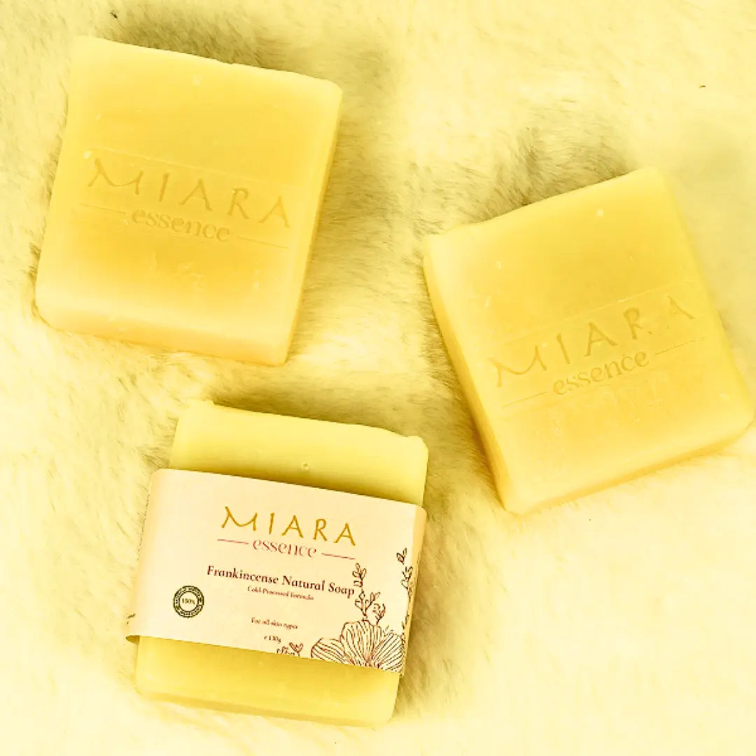 Three yellow bars of Miara Essence Frankincense Natural soap on a soft yellow fabric background